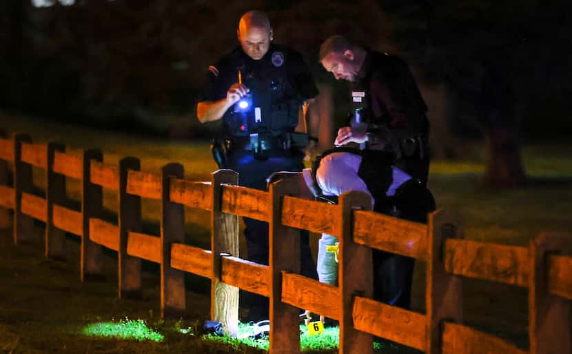 Mansfield Police officers drop a marker by a backpack left along the fenceline of Katherine...