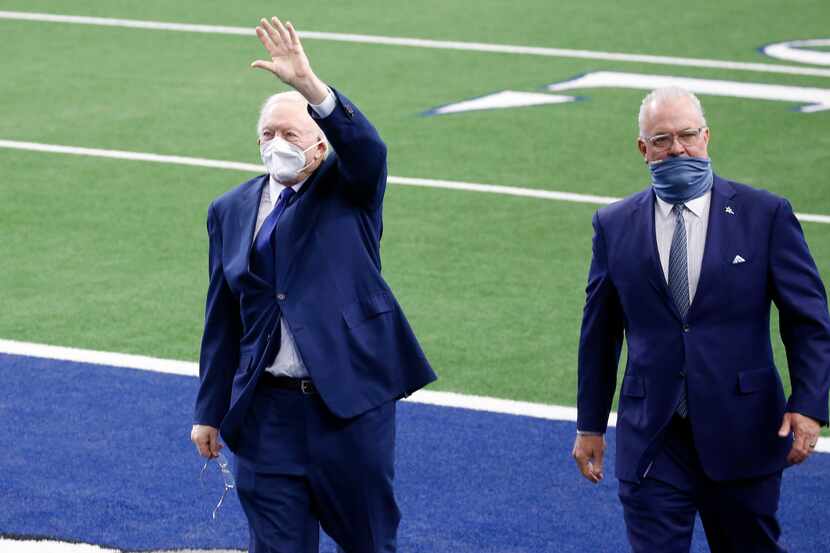 Dallas Cowboys owner and general manager Jerry Jones waves to fans as he walks off the field...