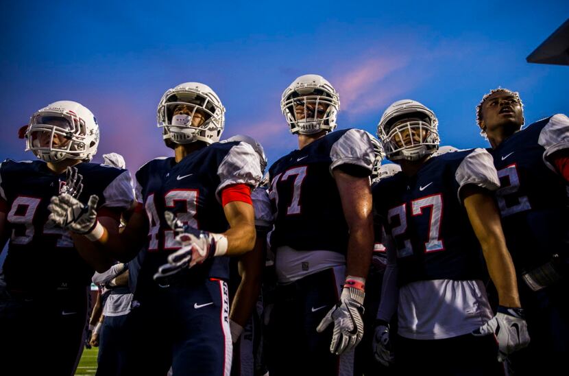 Allen football players watch their teammates from the sideline during the second quarter of...