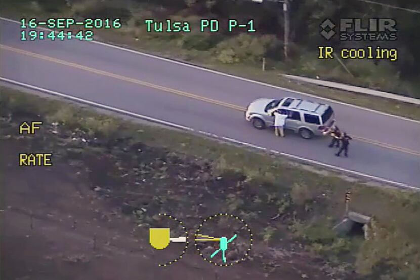 Terence Crutcher is shown with his arms up as he is pursued by police officers near his...