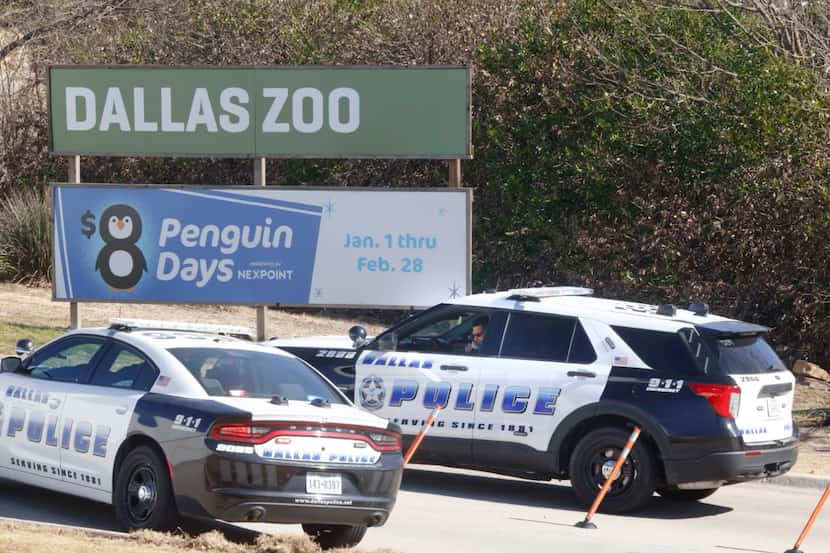 A pair of Dallas police vehicles and officers sit at an entrance at the Dallas Zoo, Friday...