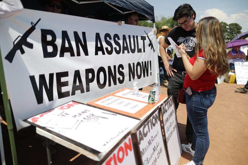 A "Ban Assault Weapons Now" sign was displayed near a voter registration table at a protest...