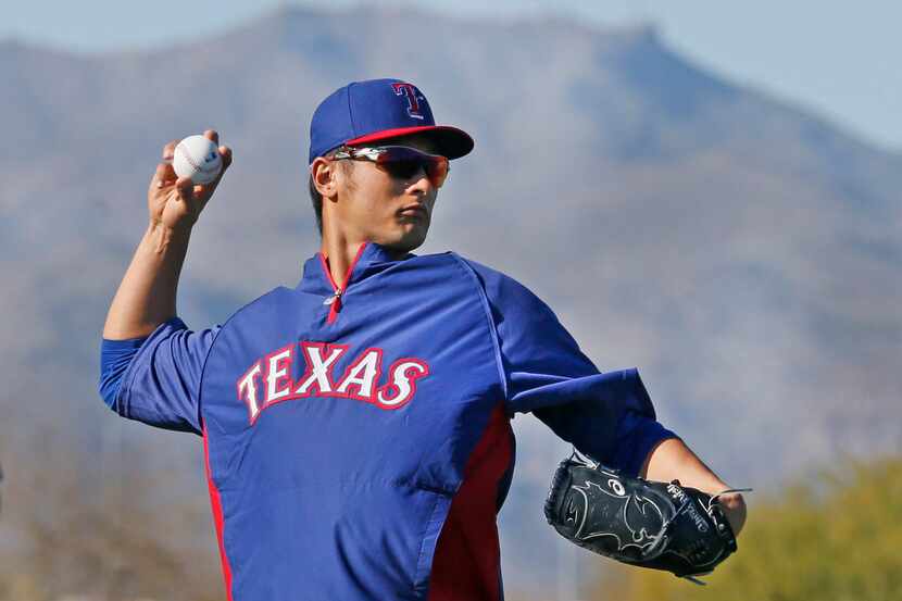 Texas pitcher Yu Darvish warms up during Texas Rangers baseball spring training in Surprise,...
