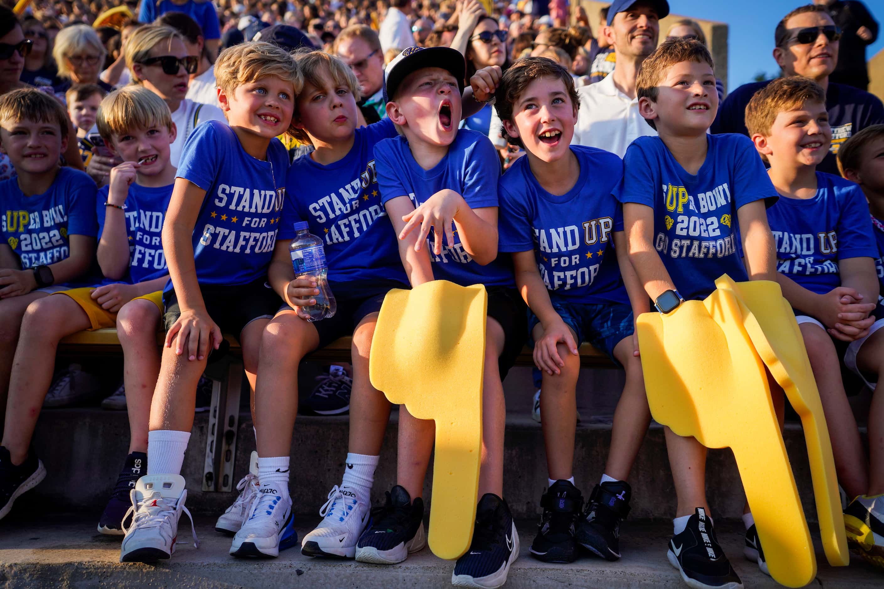 Young fans wearing “Stand Up for Stafford” t-shirts cheer before a high school football game...