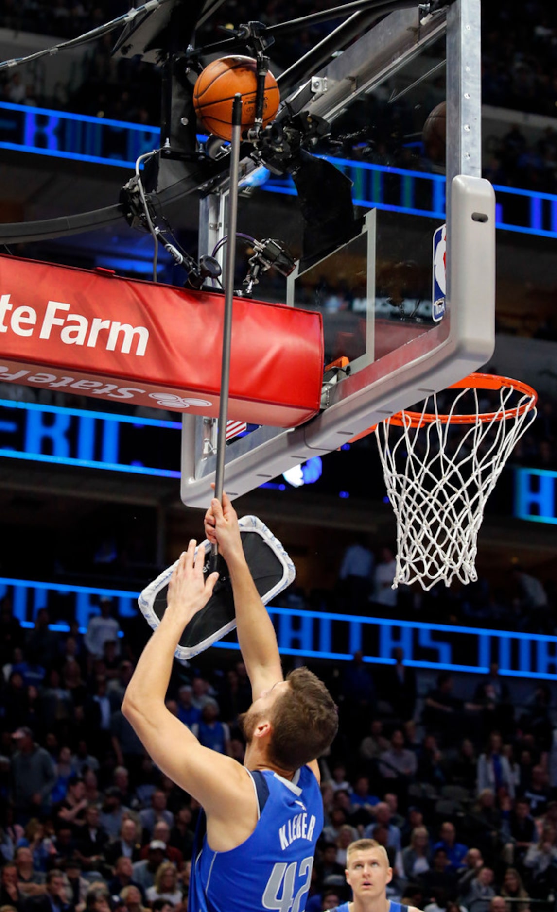 Dallas Mavericks forward Maxi Kleber (42) uses a floor mop to dislodge a ball stuck behind...