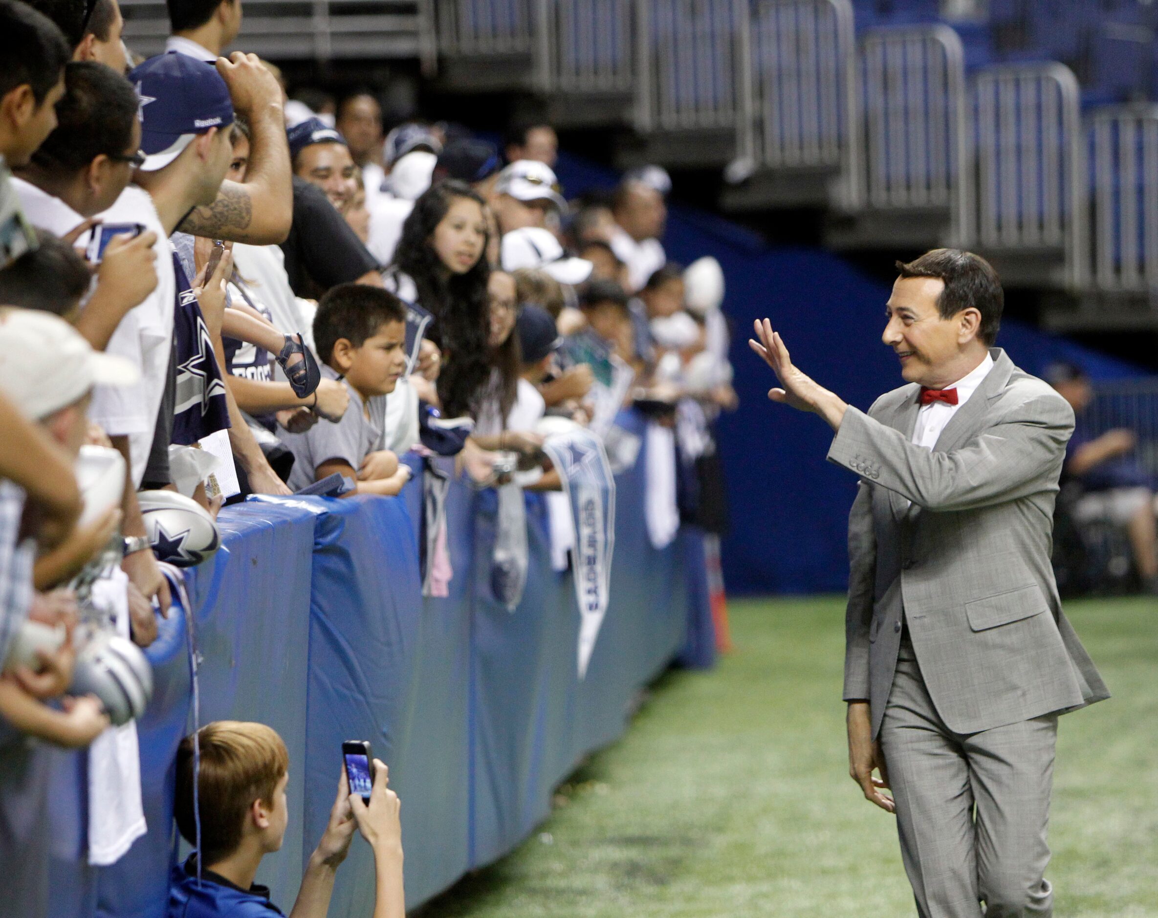 Entertainer Pee-wee Herman (Paul Reubens) waves to the fans after practice at Dallas Cowboys...