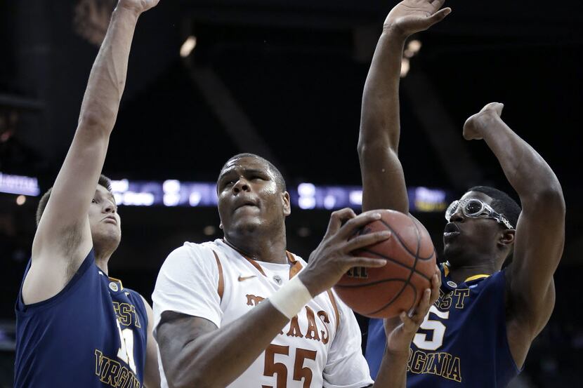 Texas' Cameron Ridley (55) looks to pass the ball under pressure from West Virginia's Nathan...