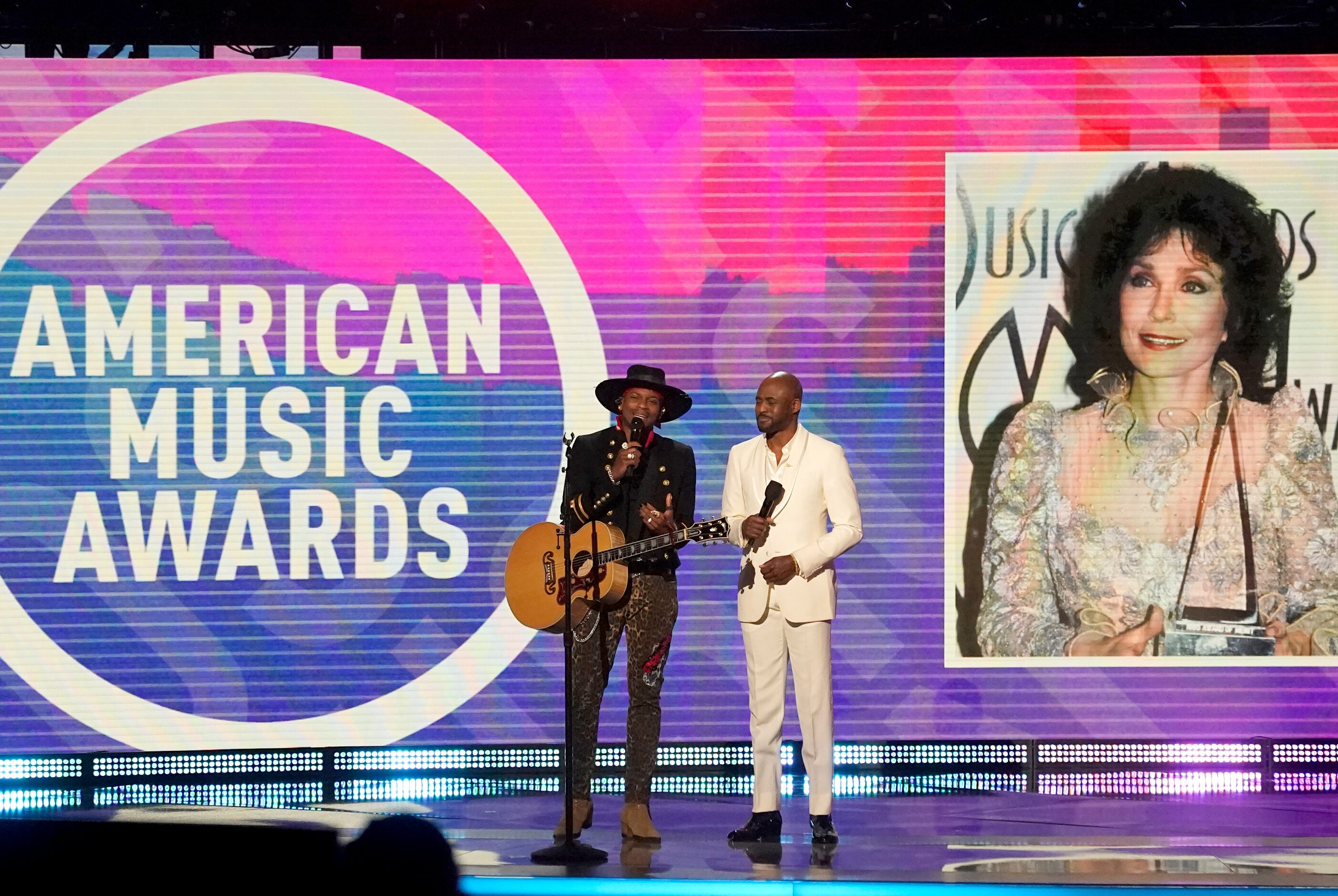 Jimmie Allen, left, and host Wayne Brady speak onstage during a tribute to the late Loretta...