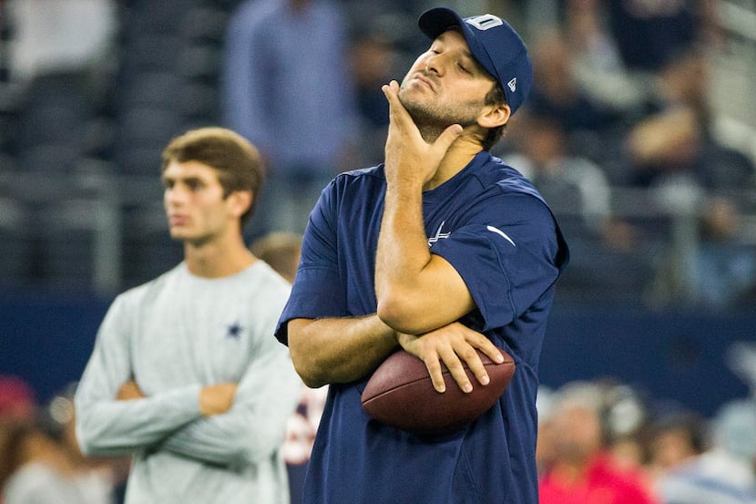 Dallas Cowboys quarterback Tony Romo watches his teammates warm up before an NFL football...