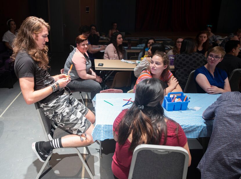 Garret Storms (Timothy) works on making a puppet at a patron table in the immersive...