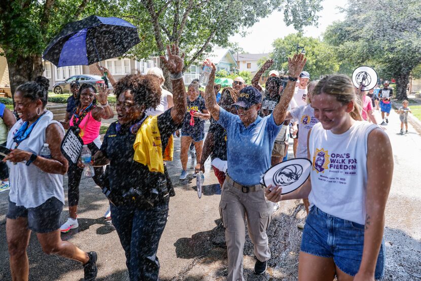 Crowd cooled off as they walk by hose water during Opal's Walk for Freedom on Monday, June...