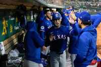 Texas Rangers' Evan Carter, center, celebrates with teammates in the dugout after scoring...