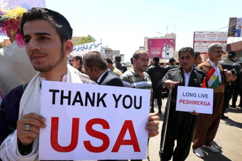 Iraqi Kurds and Iraqi Christians display signs thanking America during a demonstration in...