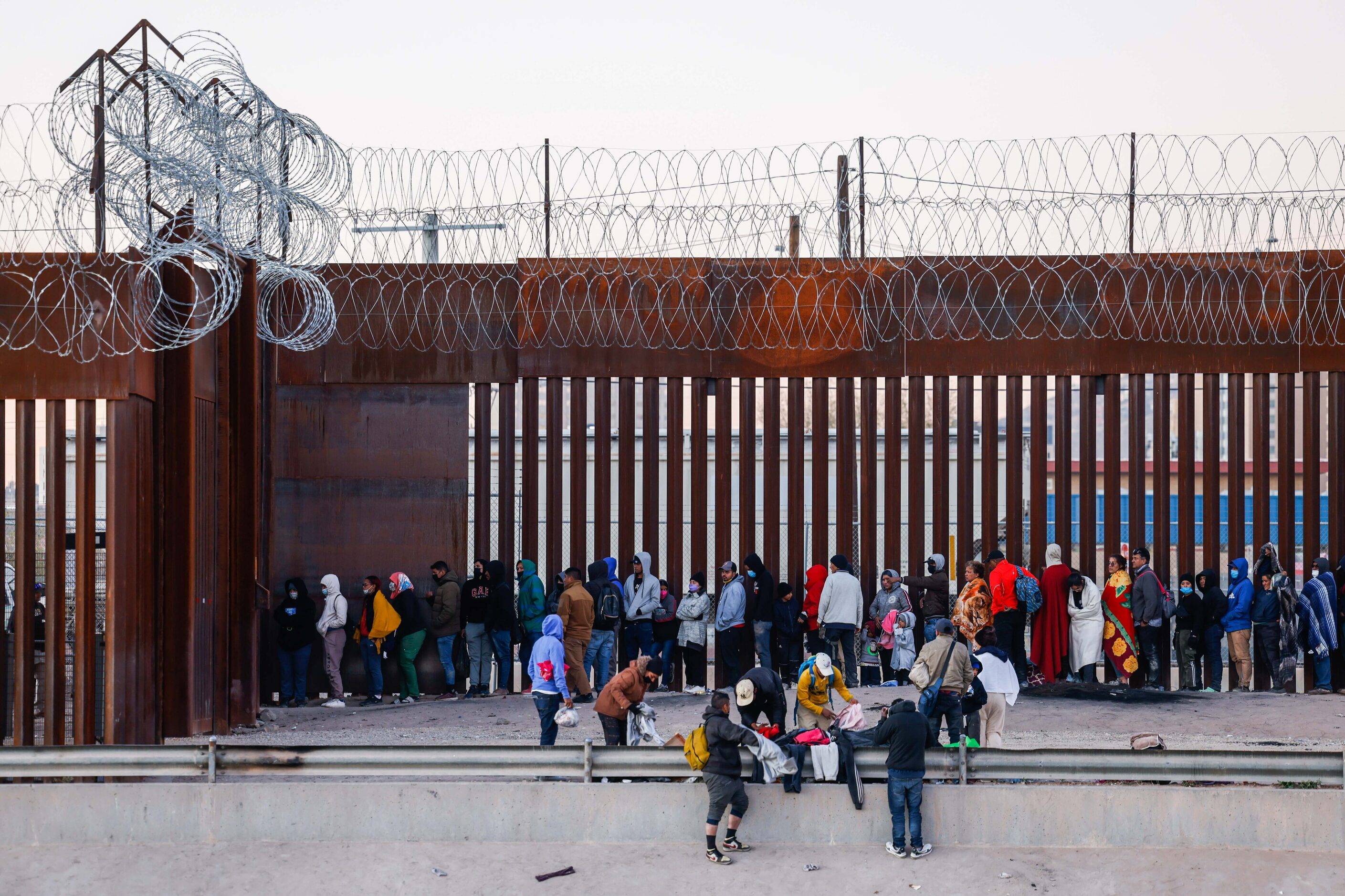 Migrants stand in line at a US-Mexico border gate from the banks of the Rio Grande River in...