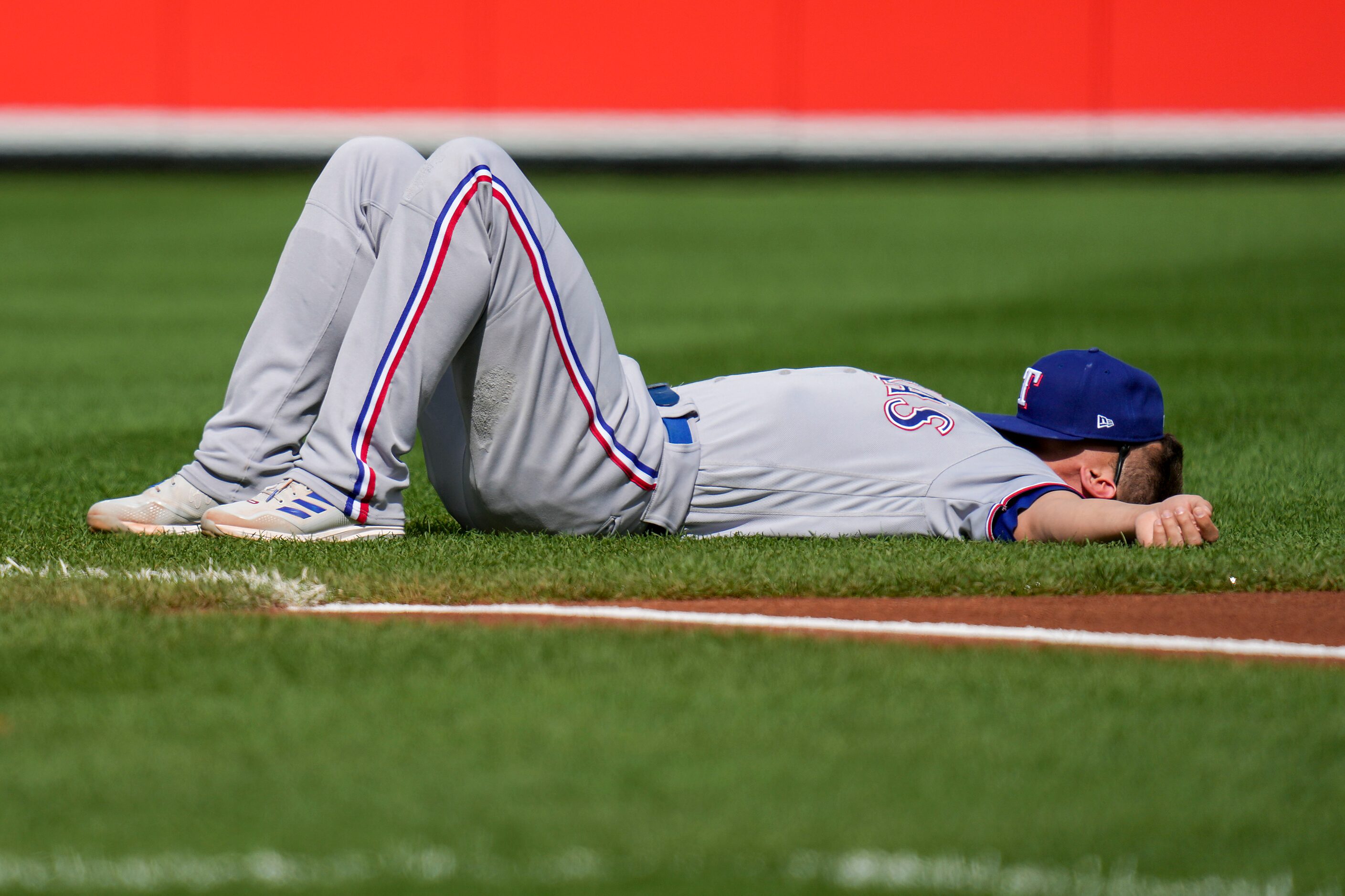 Texas Rangers shortstop Corey Seager lies on the field before Game 1 of an American League...