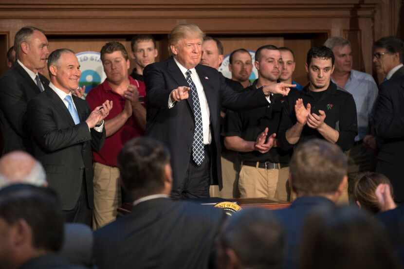 President Donald Trump, flanked by coal miners, after signing an executive order directing...