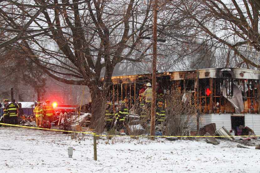 In this Jan. 20, 2014 photo, firefighters investigate a fatal fire in a mobile home in...