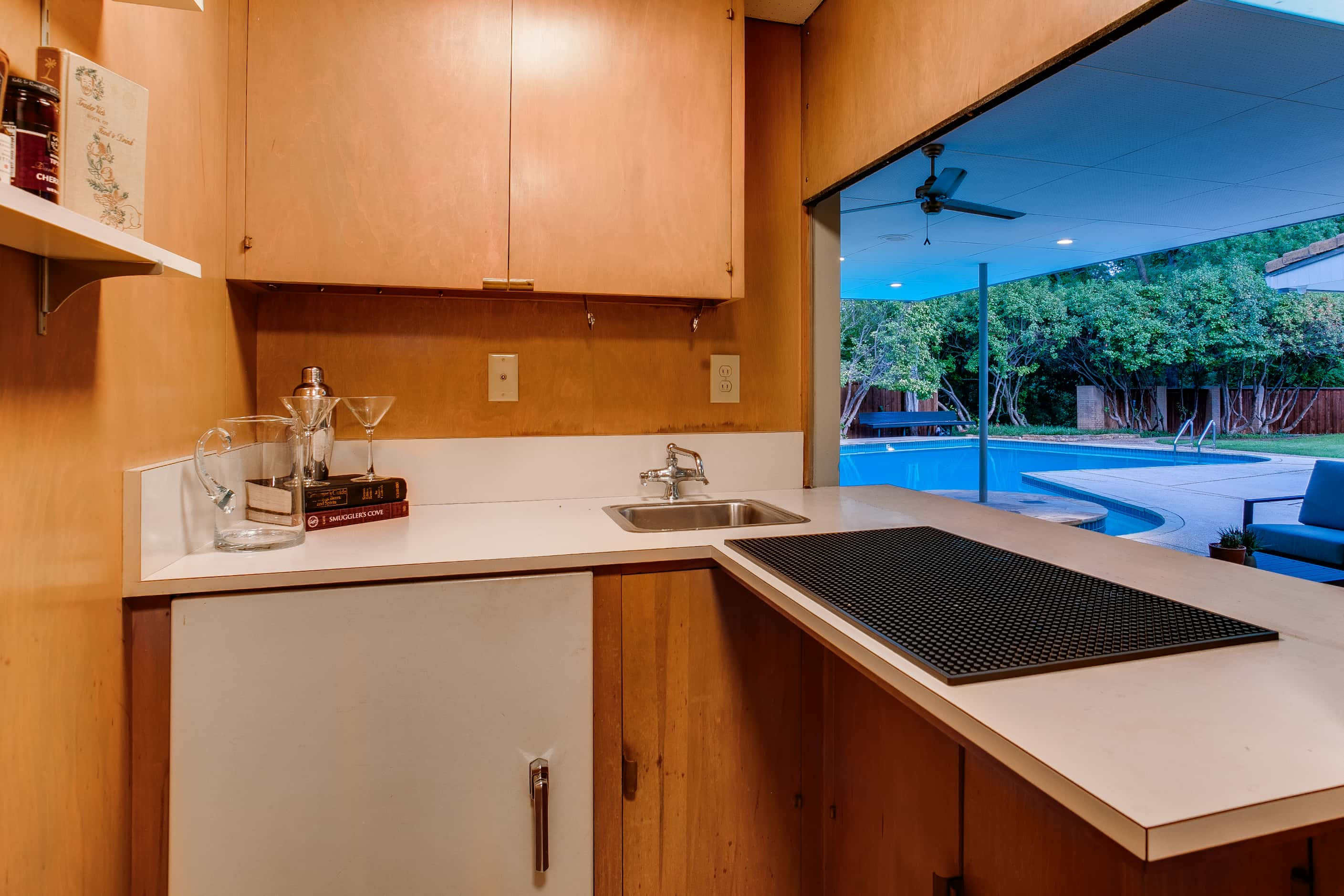 Inside of small wet bar area, pool and outdoor patio visible in background