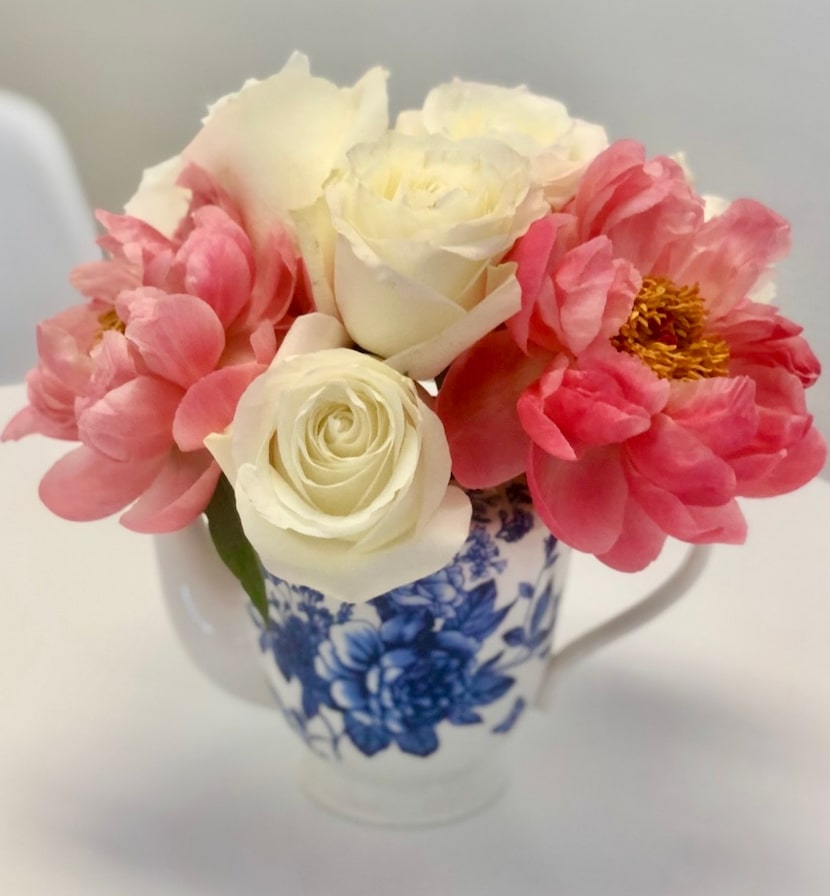 Blue and white teapot on a table with pink and white flowers