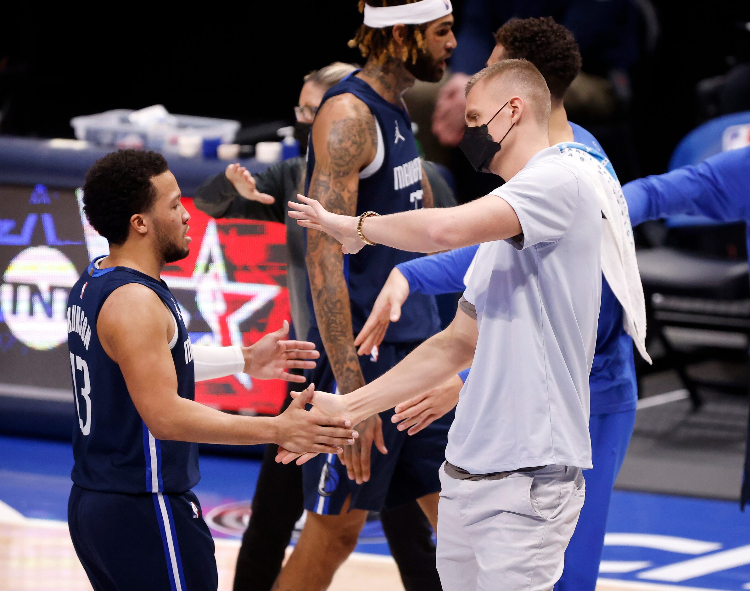 Dallas Mavericks injured center Kristaps Porzingis (right) congratulates guard Jalen Brunson...