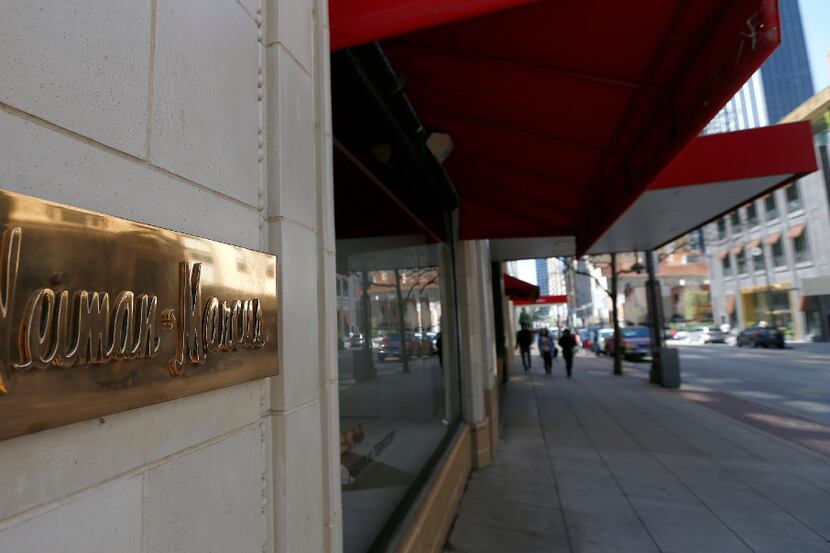 File photo: Pedestrians are reflected in a sign of Neiman Marcus on Main Street in downtown...