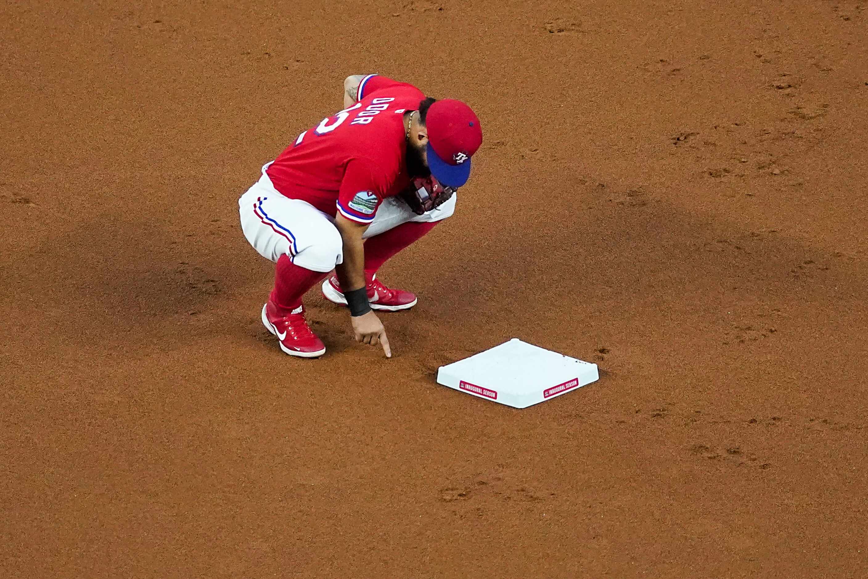 Texas Rangers second baseman Rougned Odor makes markings in the dirt behind second base...