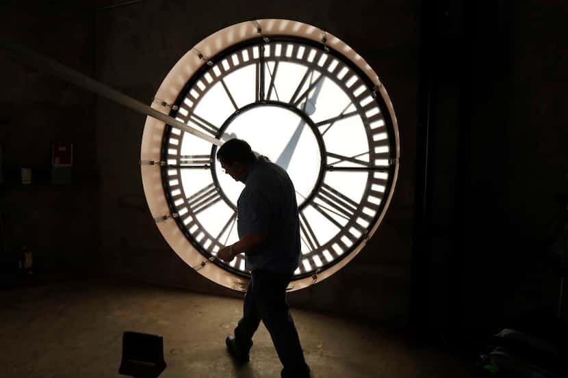 Historic clock restoration specialist Chuck Roeser of Lockport, N.Y., ducks under one of...