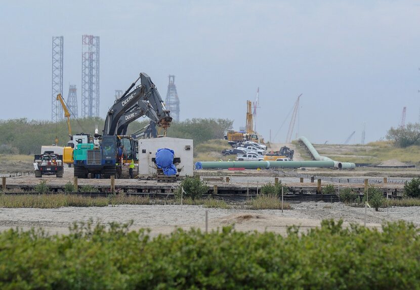 Construction crews work inside and around shelters placed along the seams of a 42-inch wide...