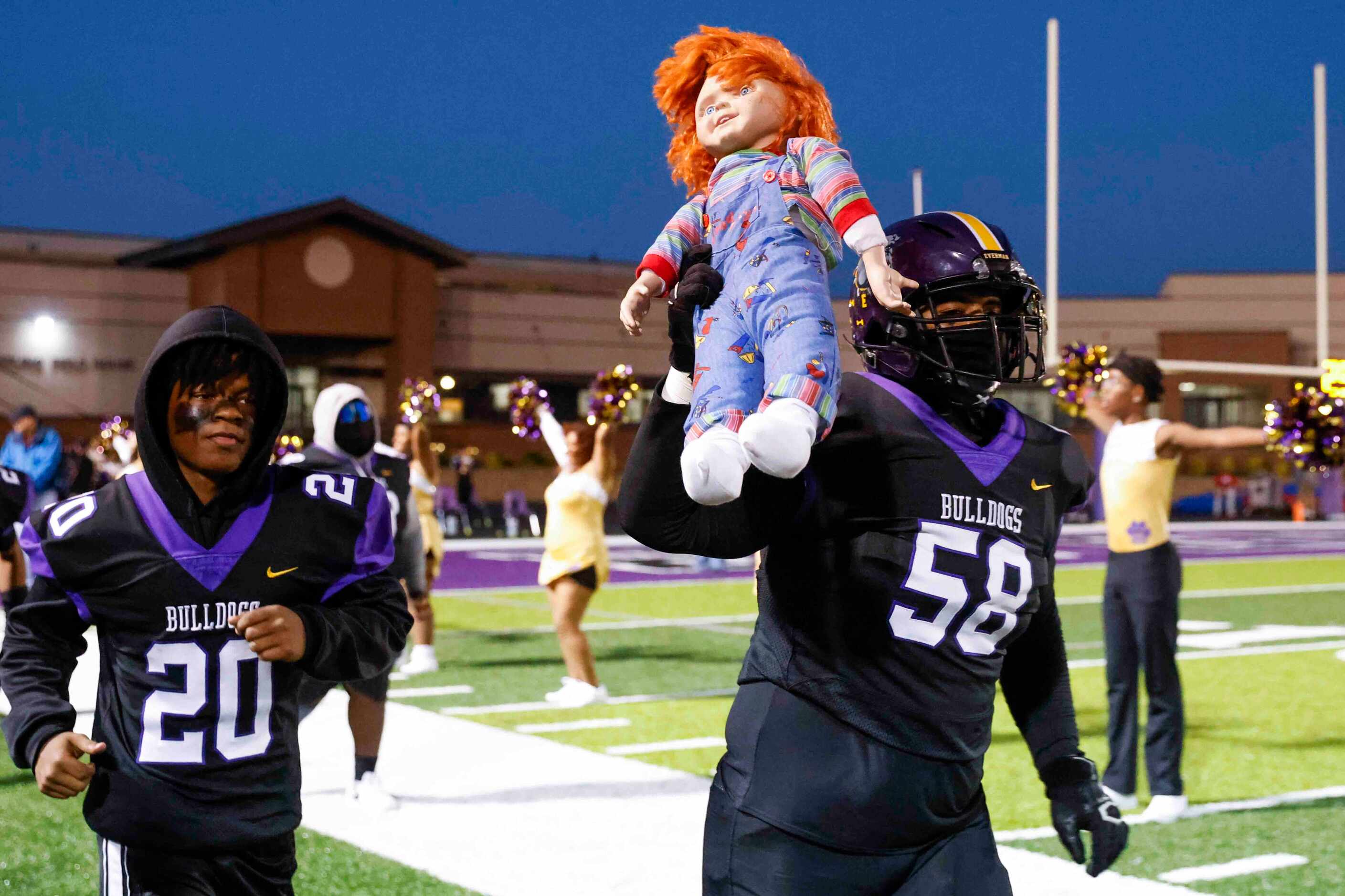 Everman High’s Jason Palmer (58) carries a Chuckie doll as he and his teammates enter the...