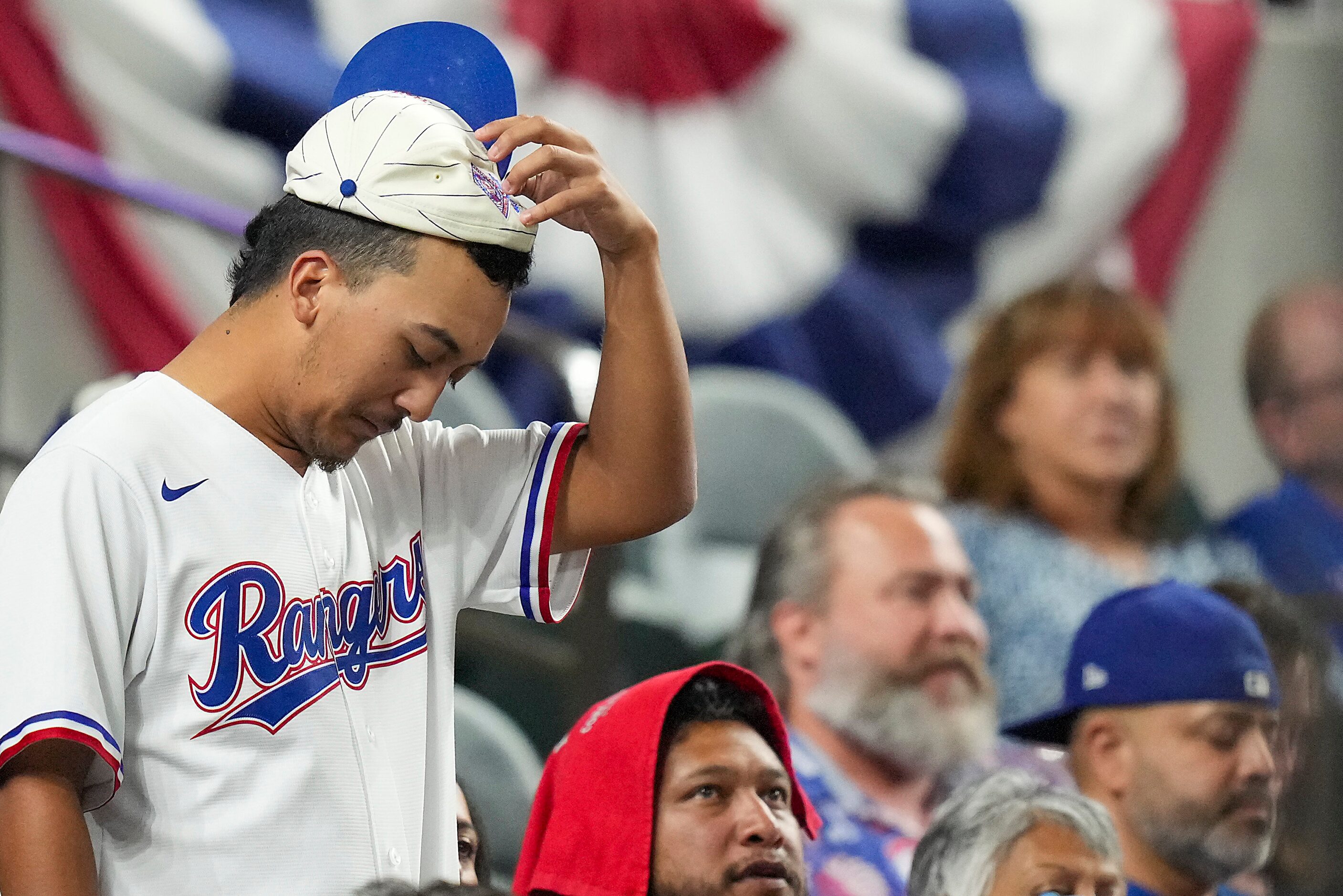 A Texas Rangers fan wears a rally cap as he reacts after the first out in the bottom of the...