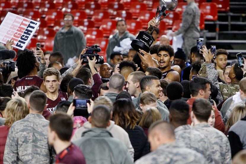 Aggies' Tyler Davis displays the trophy after a college basketball match of the Armed Forces...