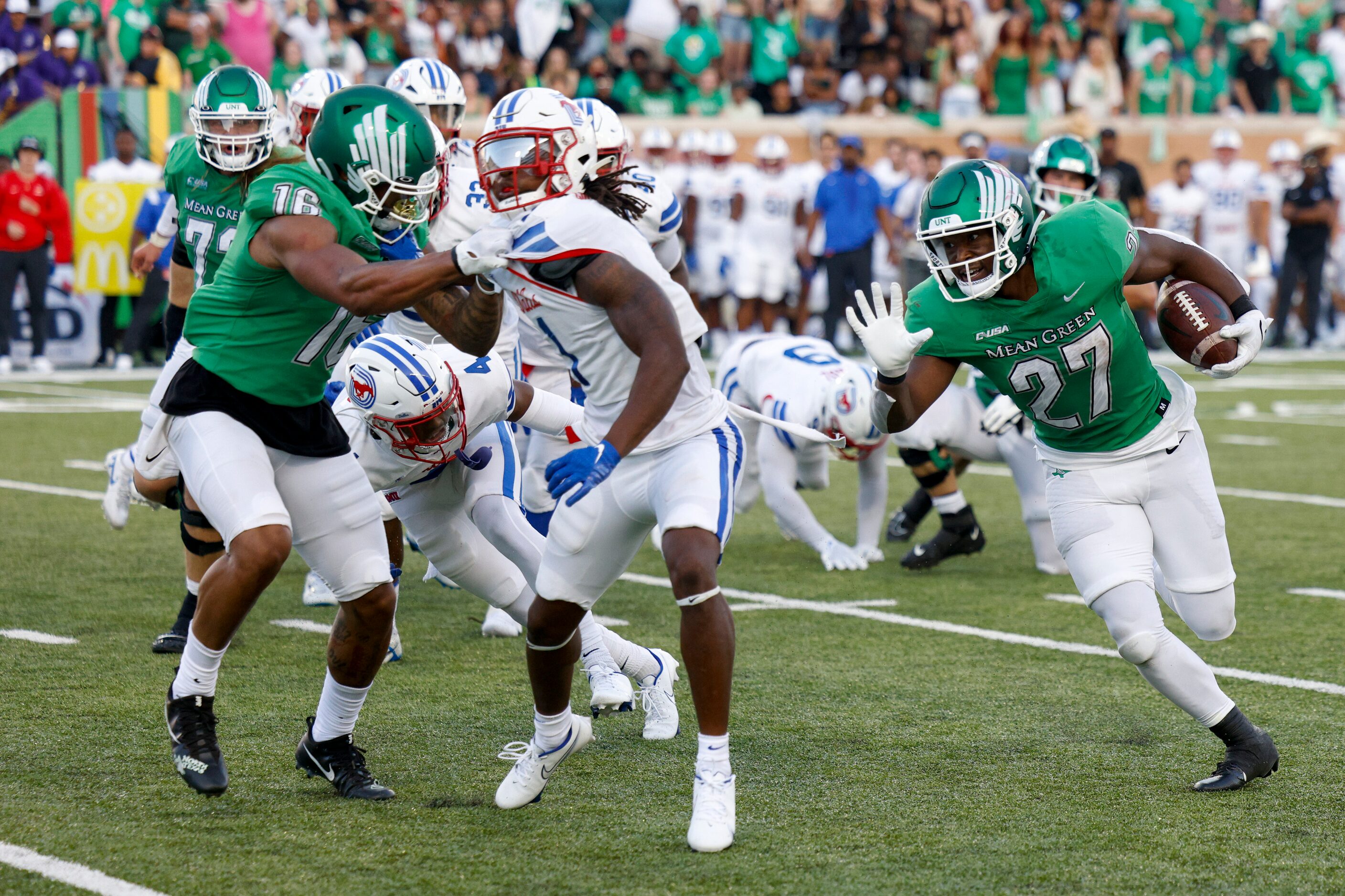 UNT running back Oscar Adaway III (27) runs the ball while defensive lineman Jonathan...