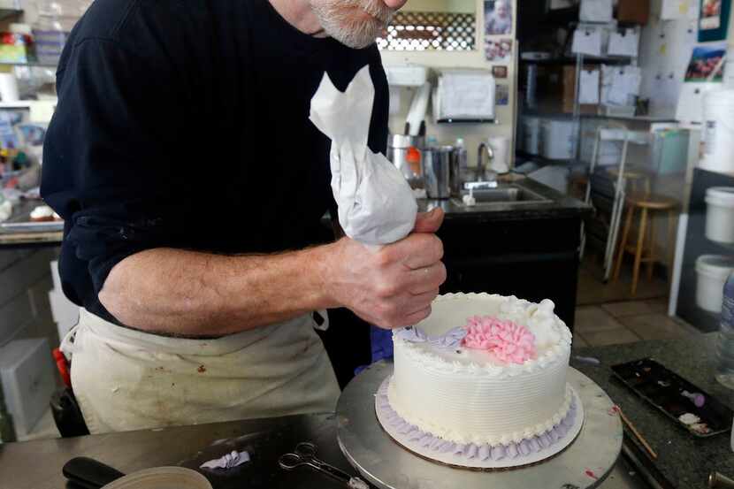 Masterpiece Cakeshop owner Jack Phillips decorates a cake inside his store in Lakewood,...