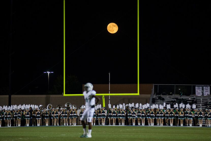 A nearly full moon rises through the uprights during the second quarter of a high school...