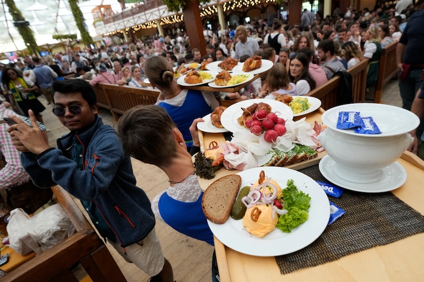 Waitresses carry traditional food plates at the Hofbraeuhaus beer tent on day one of the...