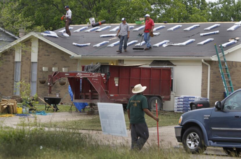 Roofers work on a home on Woodcrest Lane in Lancaster.