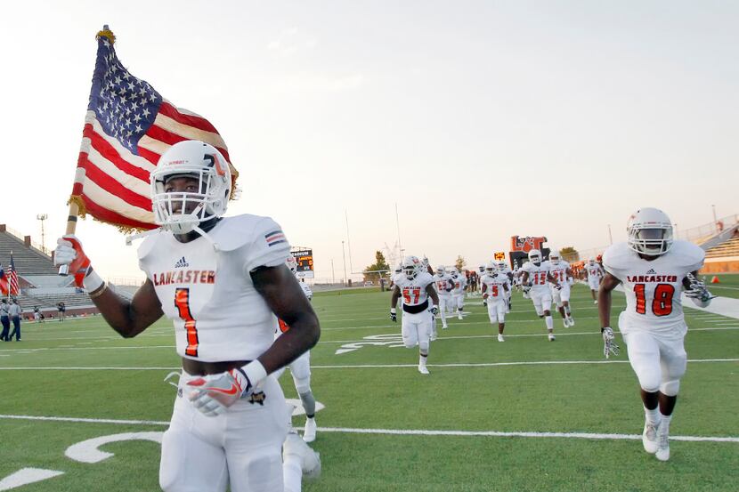 Lancaster senior wide receiver Omar Manning (1) carries the American flag onto the field...