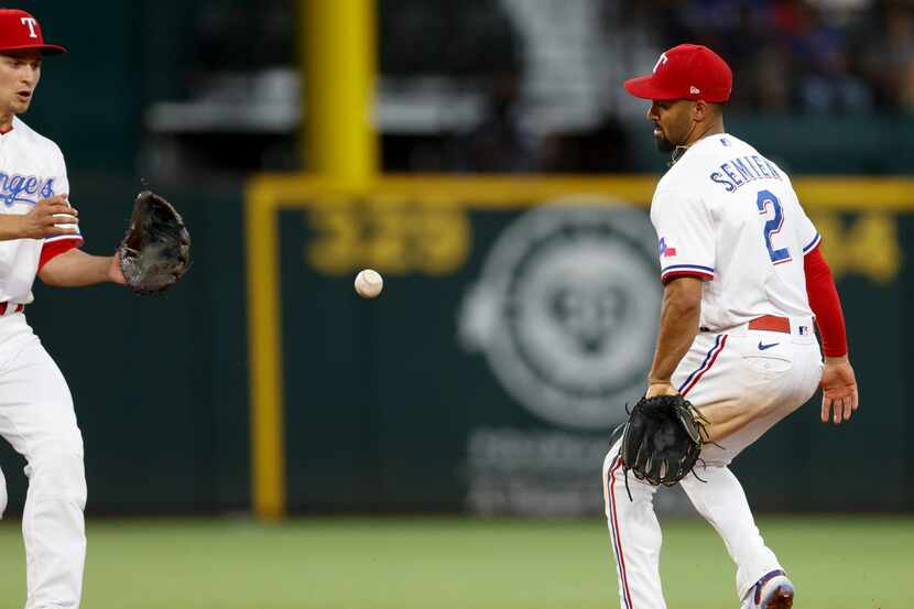 Texas Rangers second baseman Marcus Semien (2) flips the ball to shortstop Corey Seager (5)...