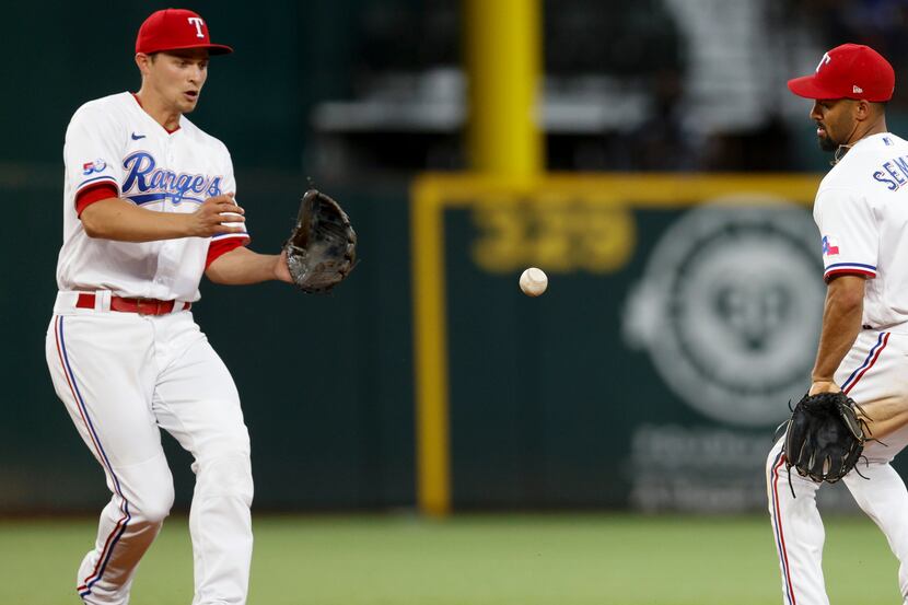 Texas Rangers second baseman Marcus Semien (2) flips the ball to shortstop Corey Seager (5)...