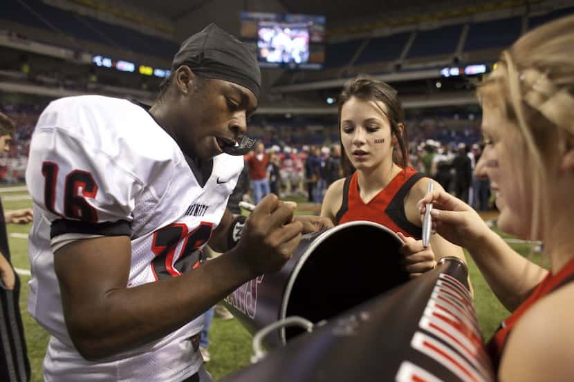 Trinity High School quarterback Willie Hubbard signs autographs for cheerleaders after their...
