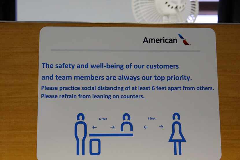Signs reminding people to keep their distance at an American Airlines gate in terminal C at...
