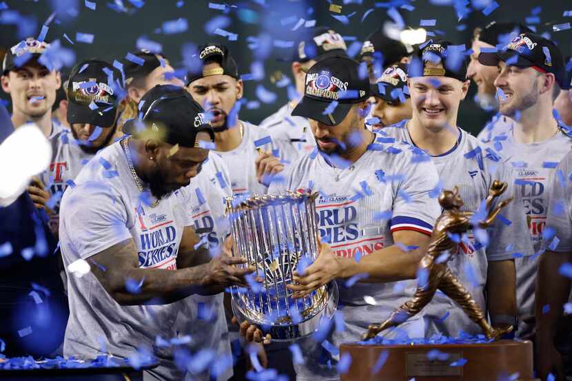 Texas Rangers’ Adolis Garcia and Marcus Semien hold the  Commissioner's Trophy after...
