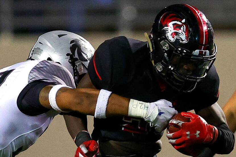 Denton Braswell running back Jaylon Burton (R) gets stopped for a short gain by Denton Guyer...