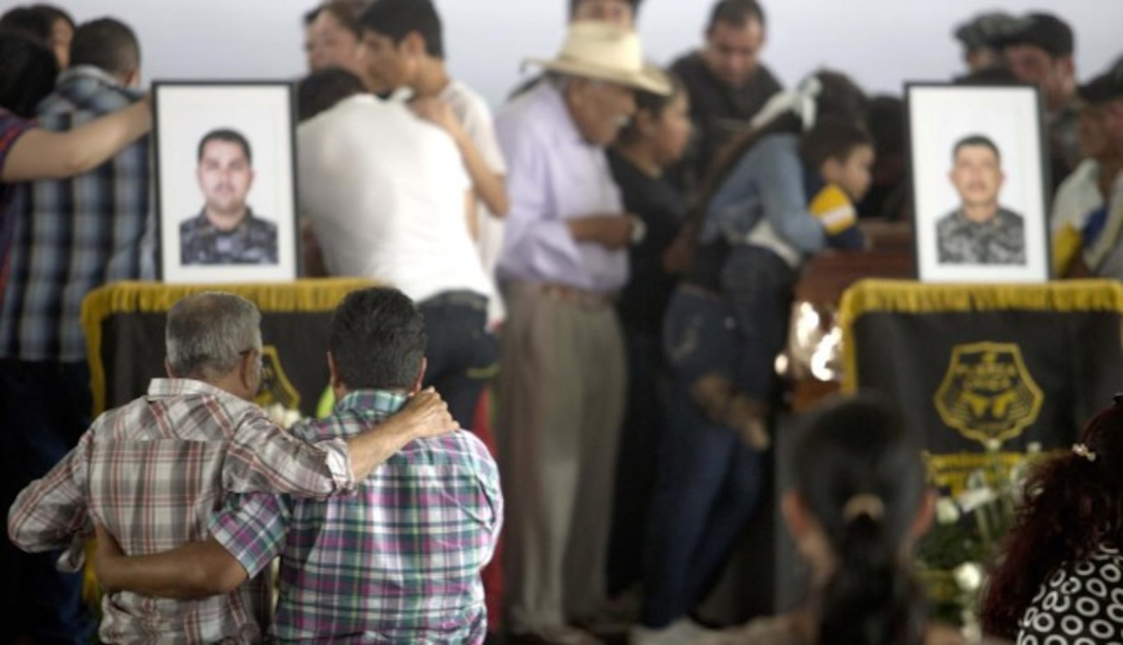 Dolientes se consuelan durante una ceremonia en honor a los 15 policías asesinados por el...