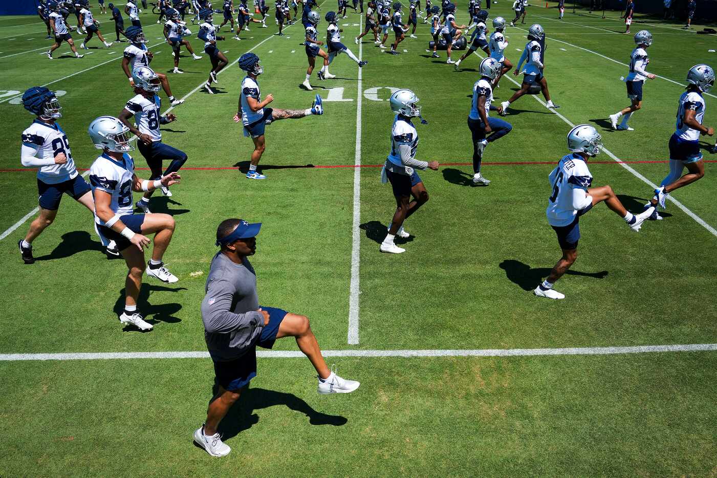 Dallas Cowboys players and coaches stretch during a training camp practice on Thursday, July...