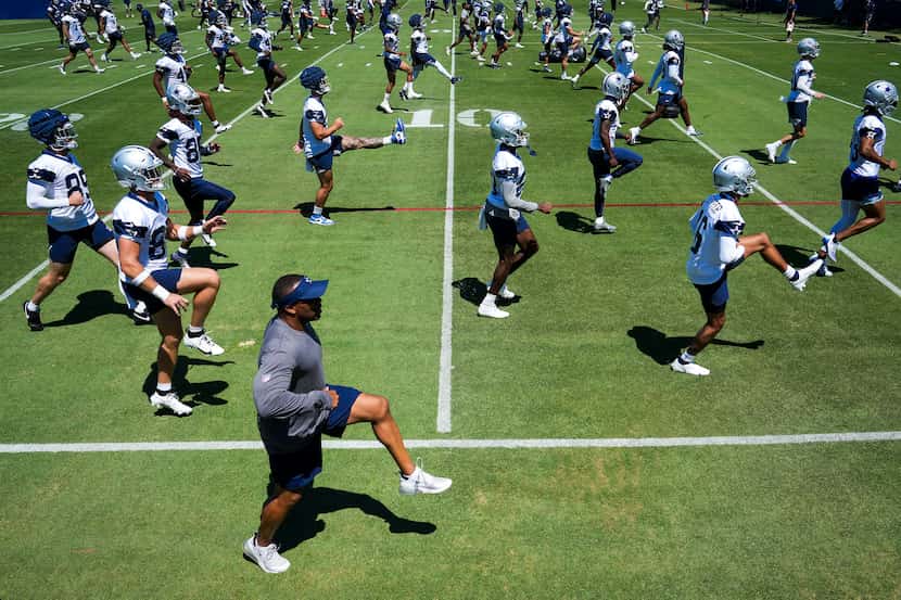Dallas Cowboys players and coaches stretch during a training camp practice on Thursday, July...