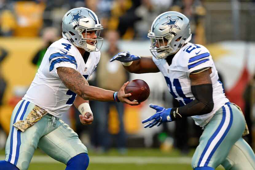 Cowboys quarterback Dak Prescott (4) hands the ball off to running back Ezekiel Elliott (21)...