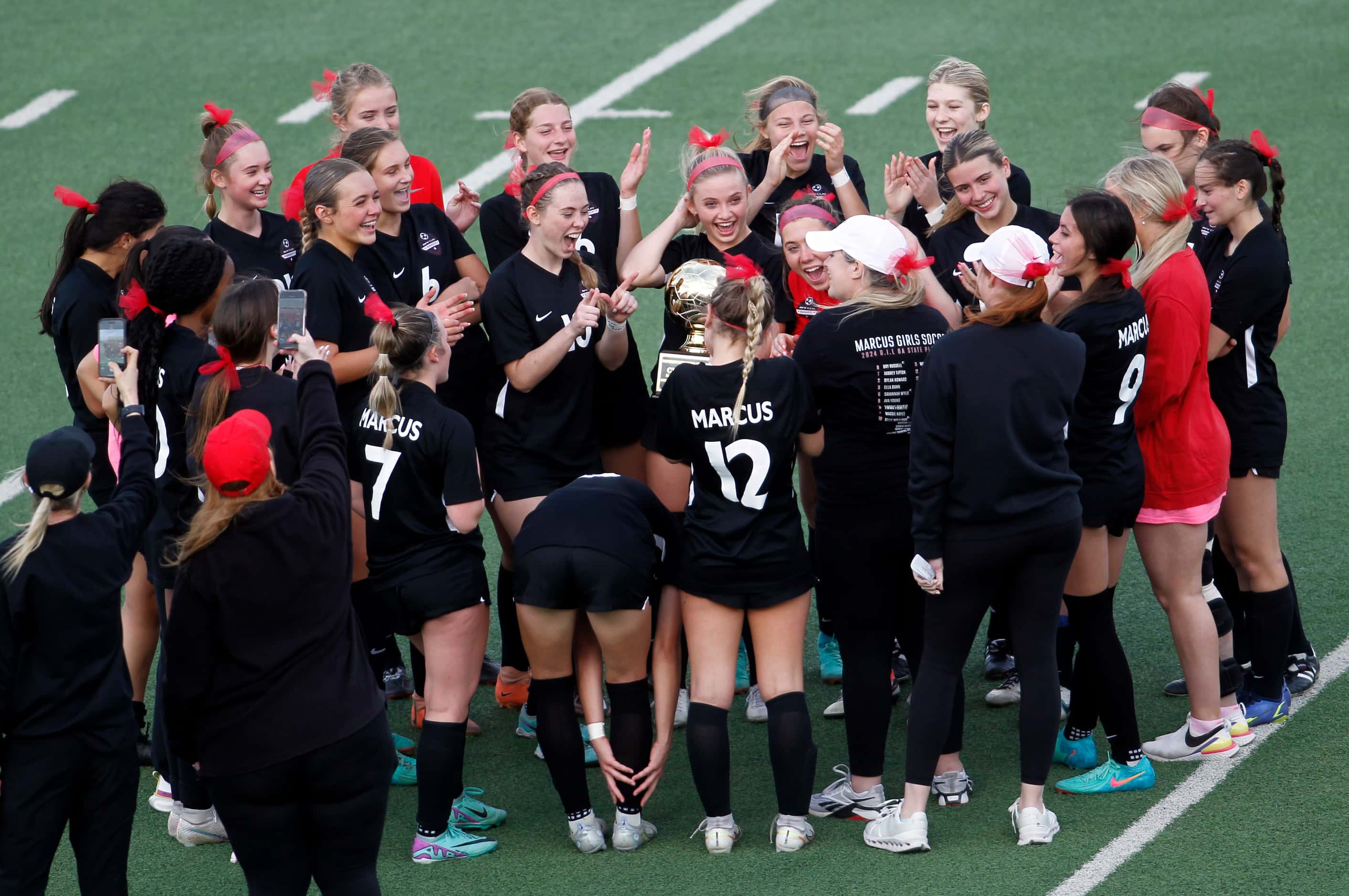 Flower Mound Marcus players react to a message shared from head coach Erin Smith, center...