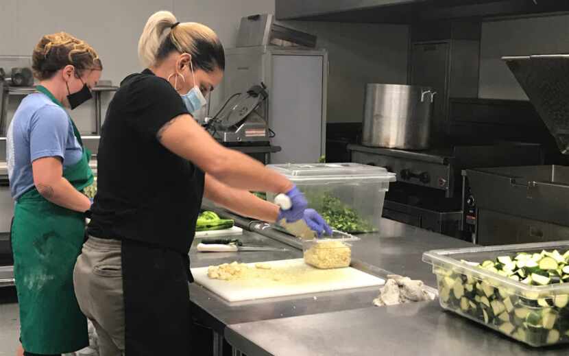 Two masked workers chop vegetables in a kitchen as part of Frito-Lay's Women's Workforce...