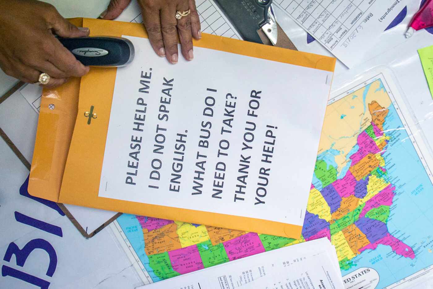 A volunteer staples a message in english to an envelope of paperwork for an immigrant to...